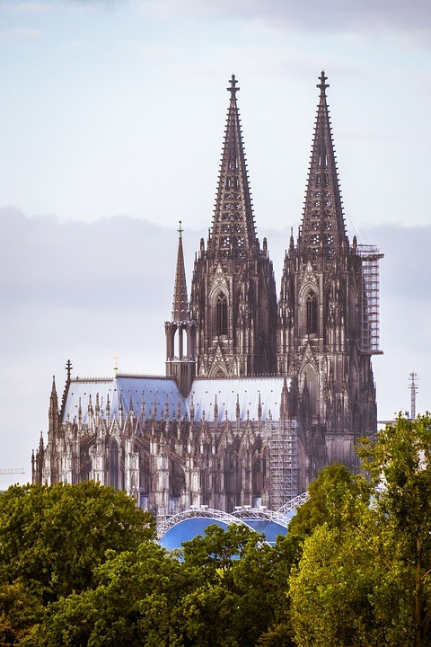 der Kölner Dom mit Bäumen im Hintergrund und blauem Himmel