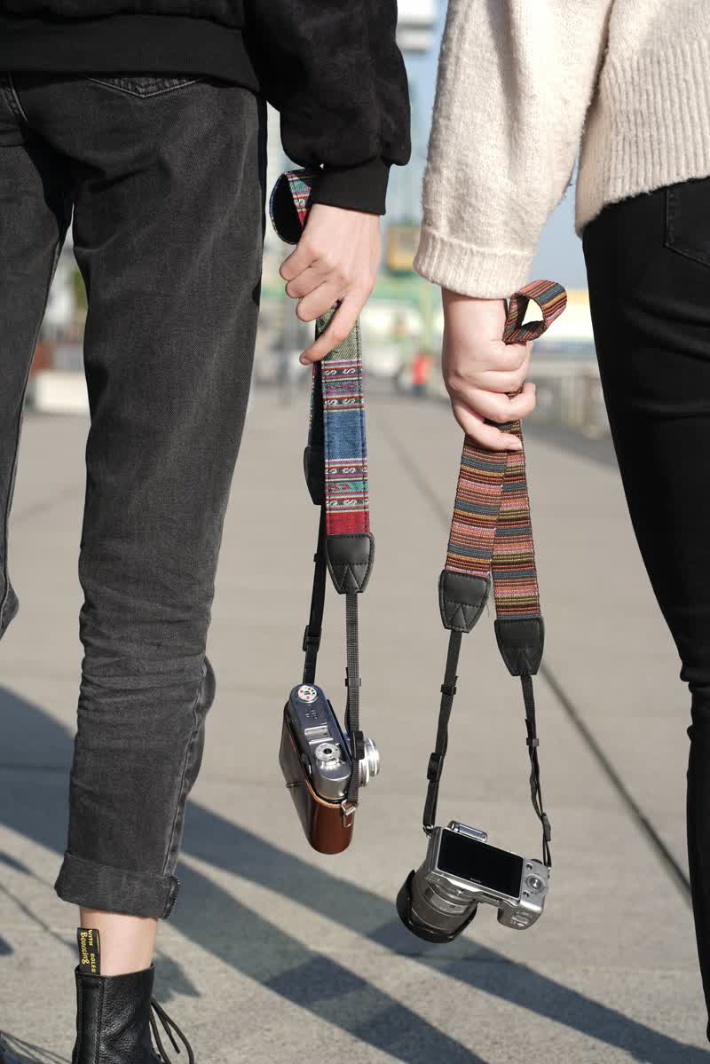zwei Mädchen mit Kameragurt der Hand ohne Gegenlicht.
