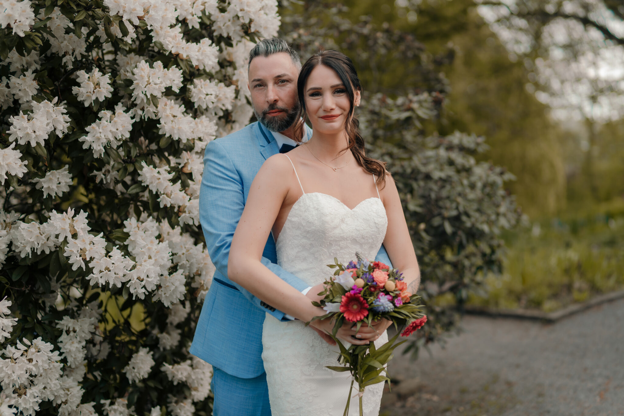 73R01478-261+Kopie Das Hochzeitspaar vor einem großen Blumenbusch
