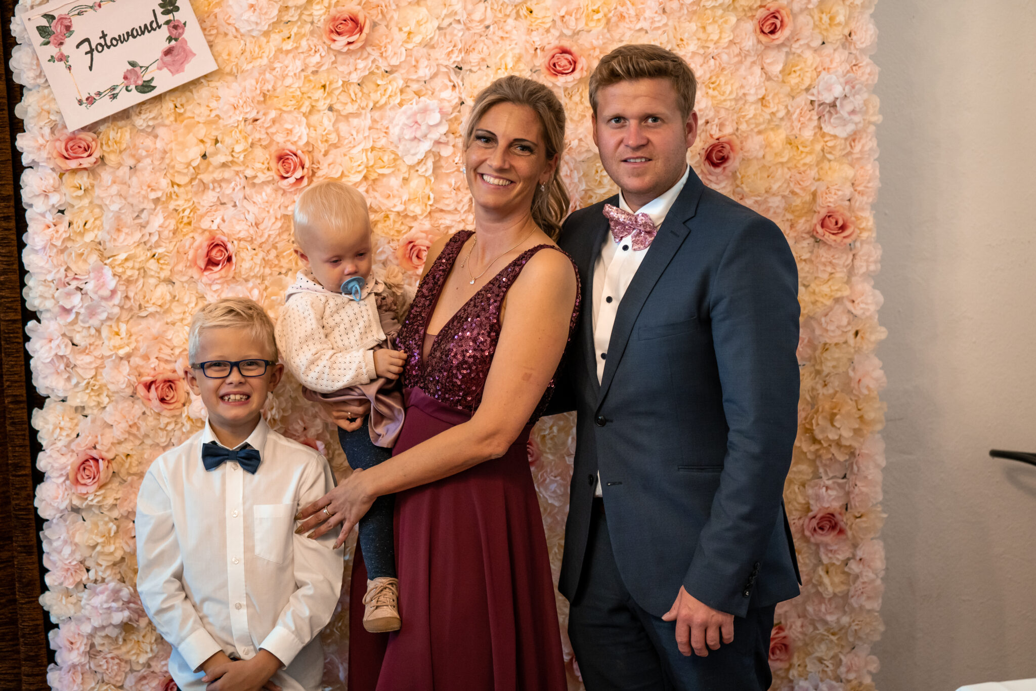 73R07772 Familienfoto vor Fotowand in Hochzeitslocation