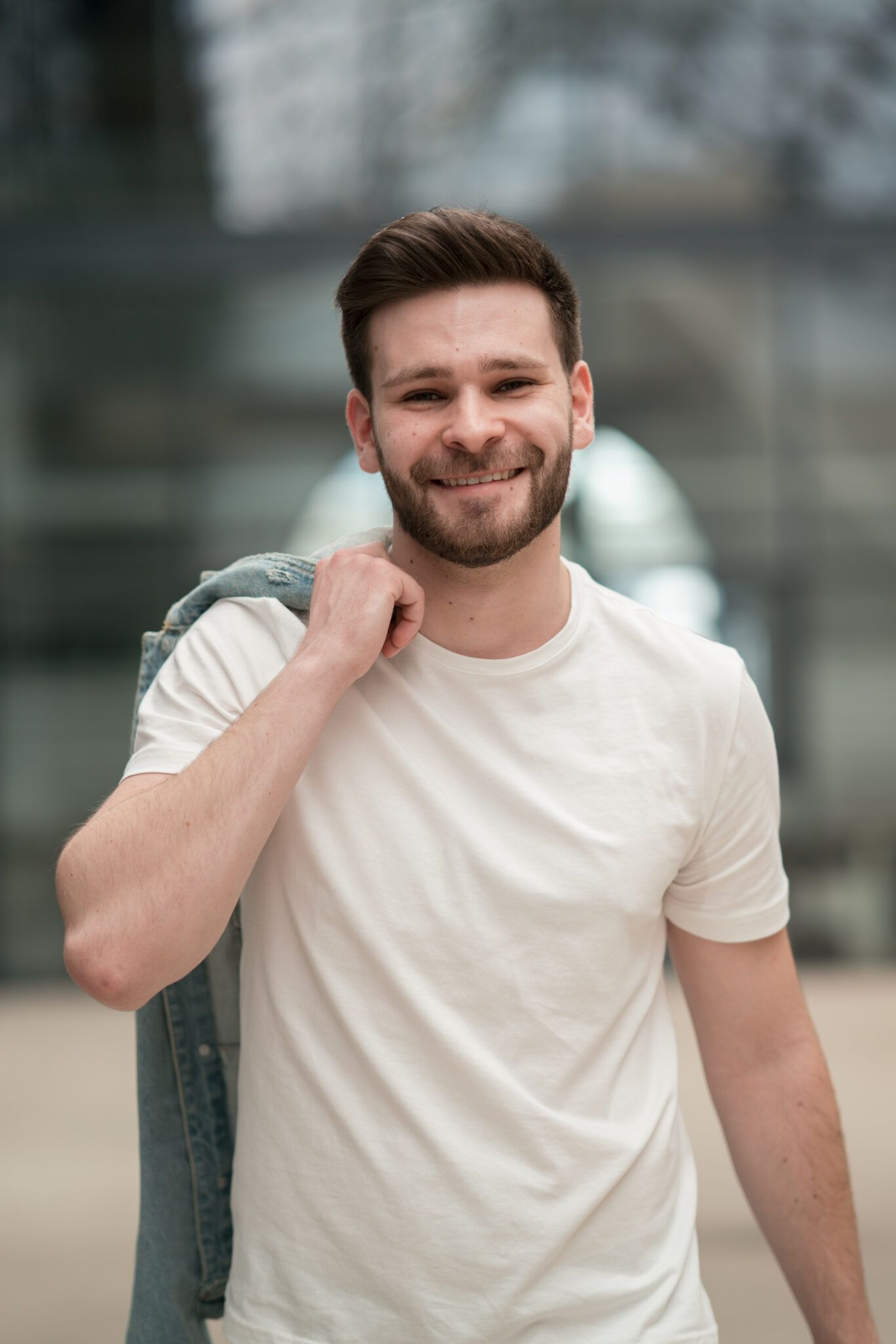 73R04125_patrickb Mann mit Bart läuft auf Industrie Gelände und hält seine Jacke über der Schulter