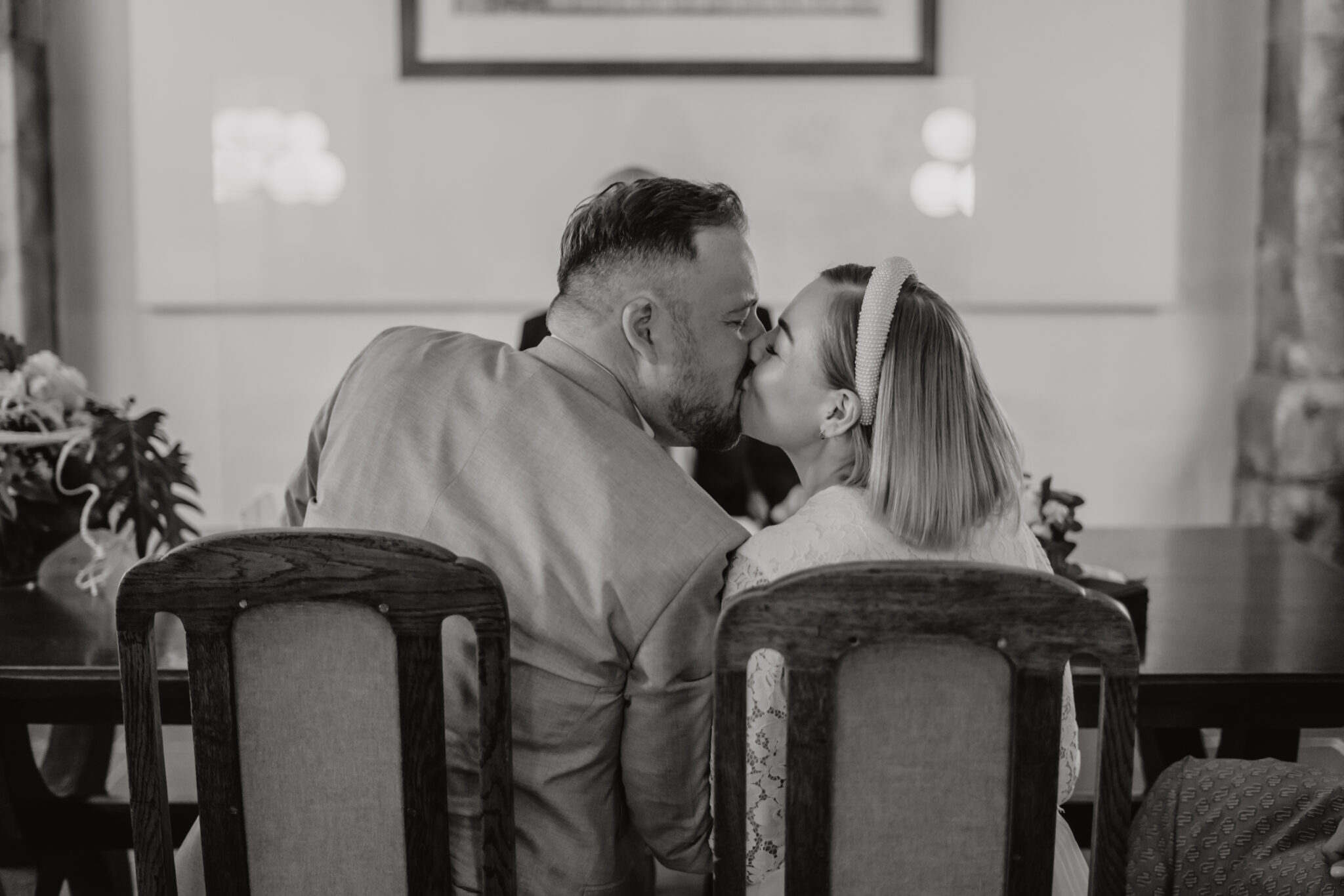 44-3 Hochzeitspaar küsst sich auf Traustühlen in Standesamt