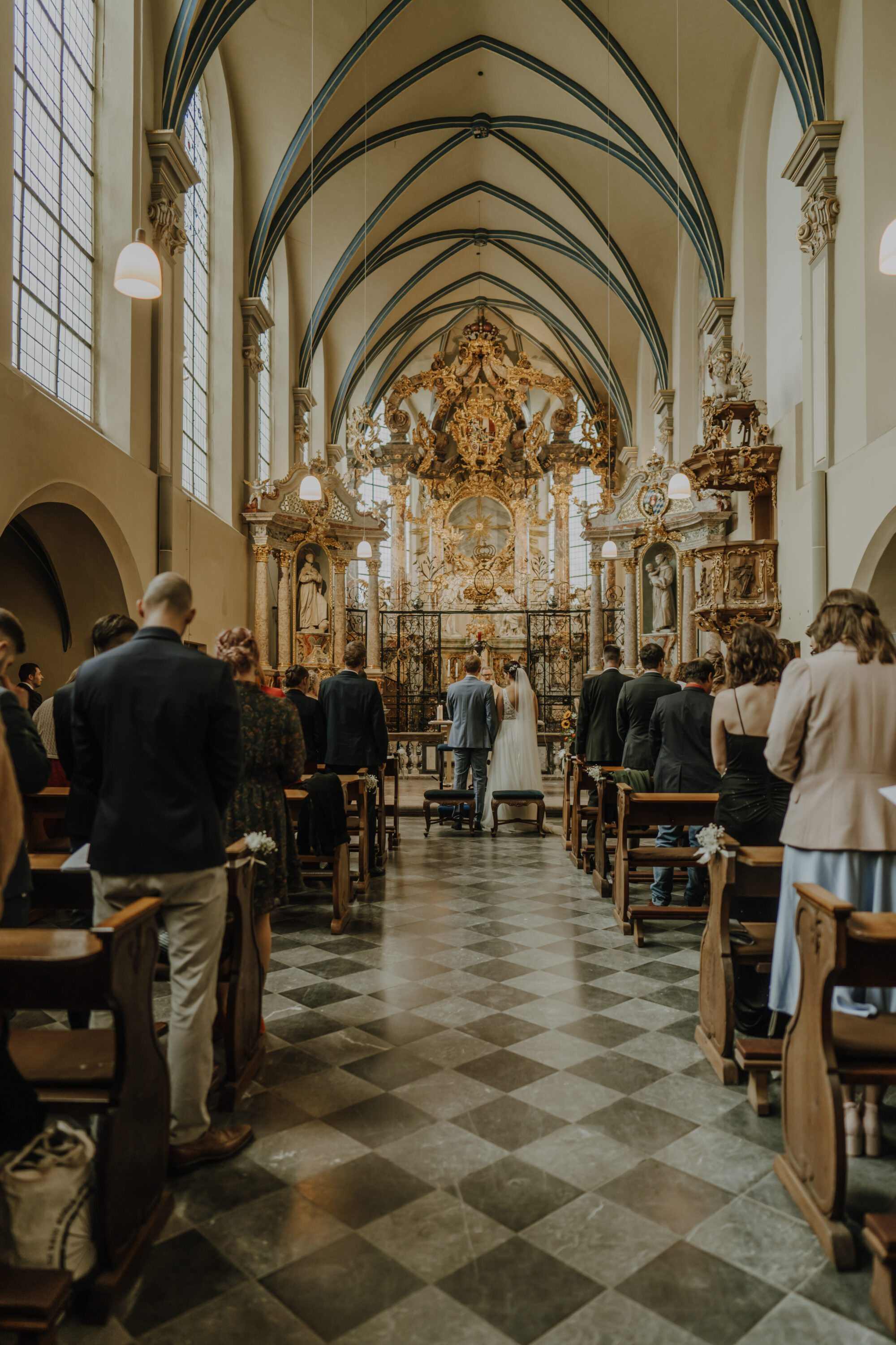 _74R5940-Inaundniklaskirchlich Brautpaar steht am Altar der Schlosskirche St. Maria von den Engeln, hohe Decken