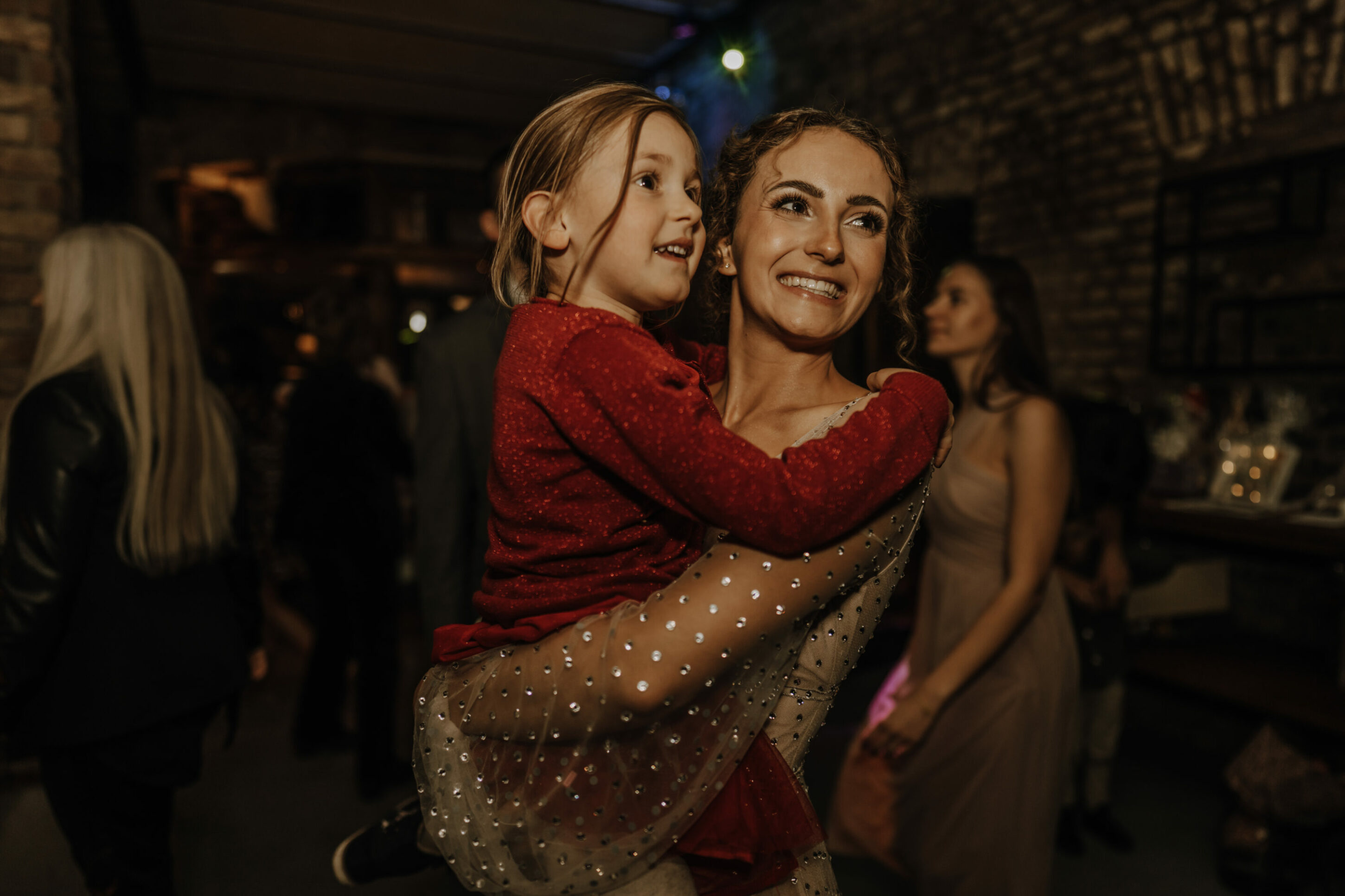 _74R6341-annaundmarkhochzeit-2 Braut, lachend, mit kleinem Mädchen auf dem Arm