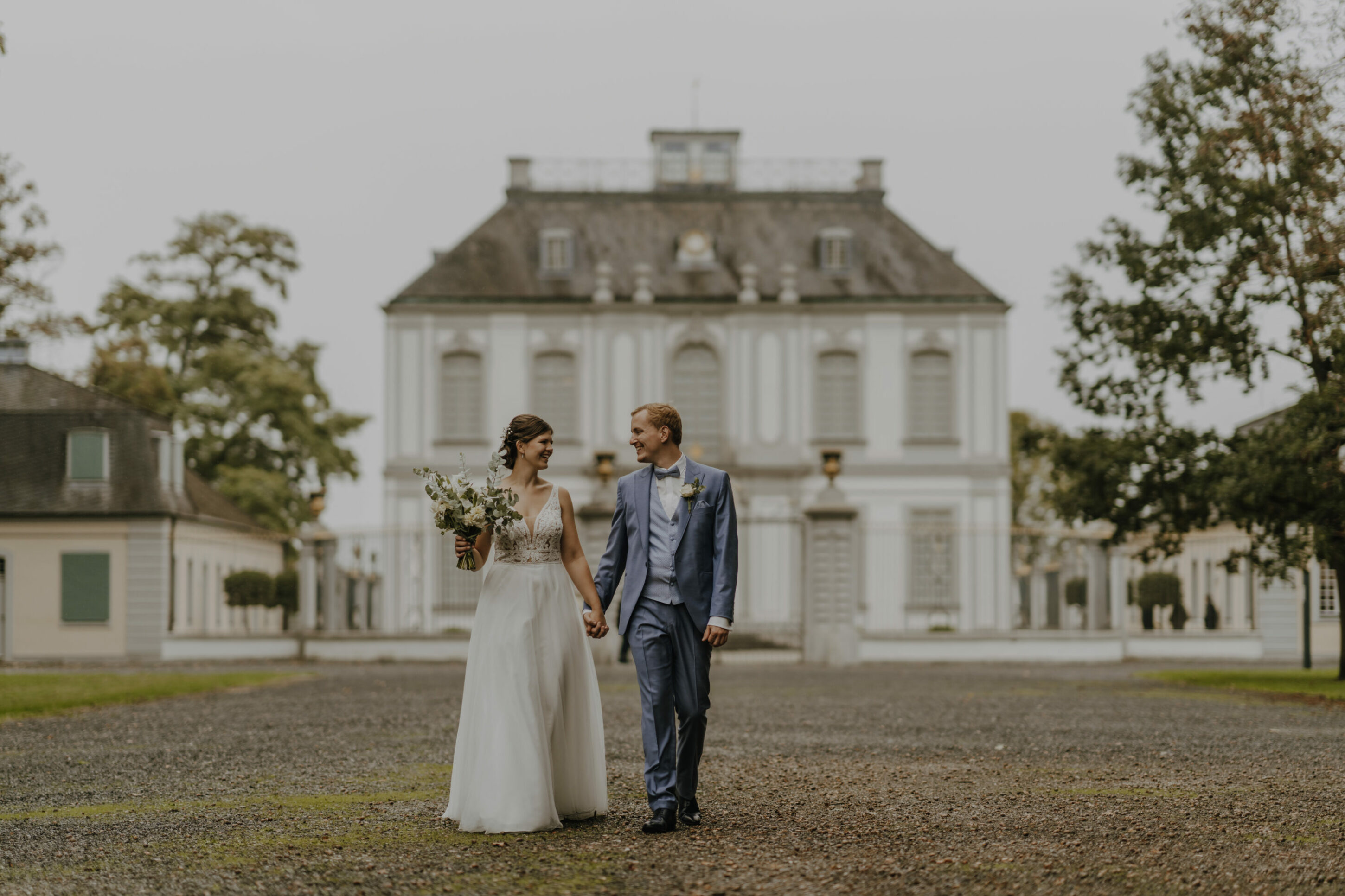 _74R9155-Inaundniklaskirchlich Hochzeitspaar läuft glücklich vor der Schlosskirche St. Maria von den Engeln