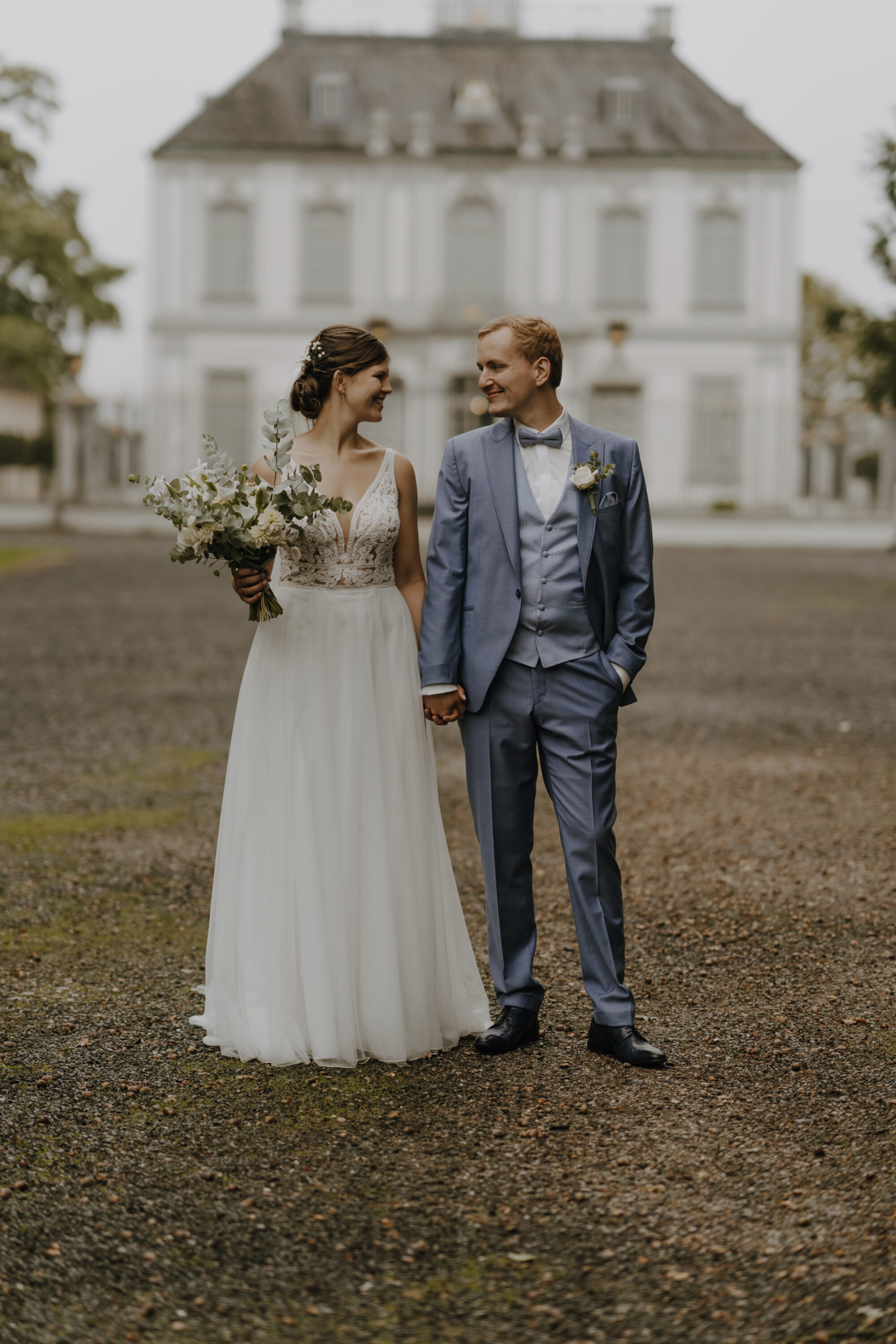 _74R9172-Inaundniklaskirchlich Hochzeitspaar steht glücklich vor dem Schloss Falkenlust
