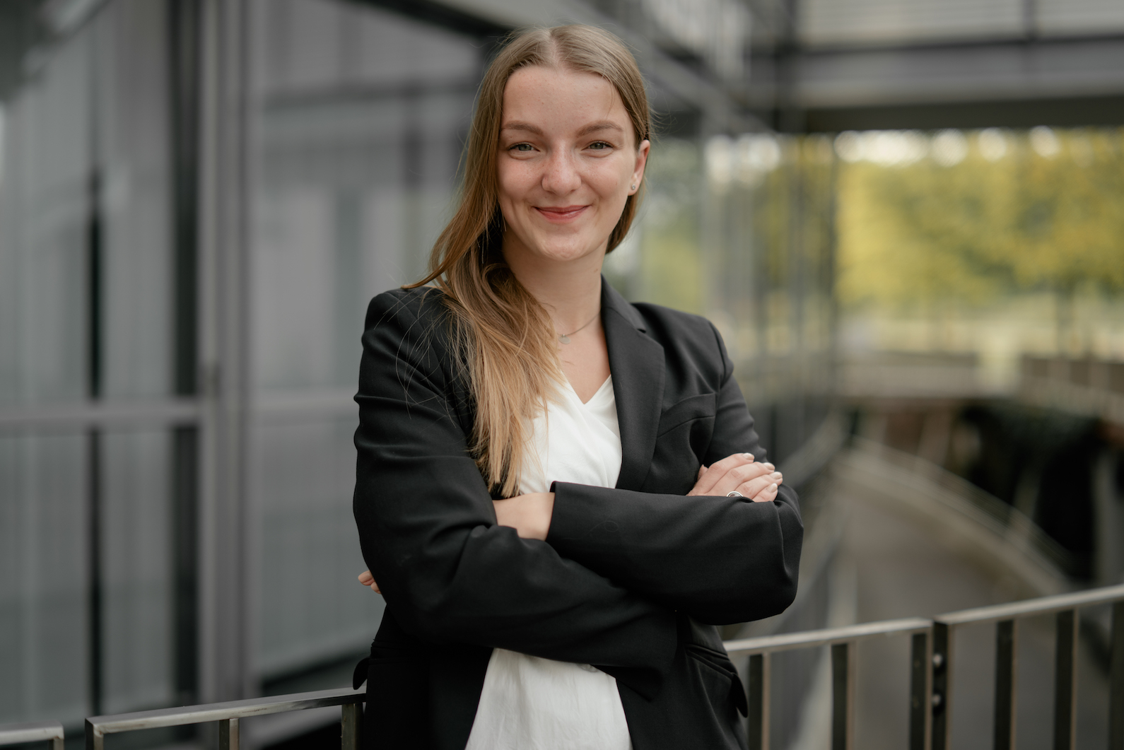 Frau im Businesslook mit verschränkten Armen lächelt in die Kamera
