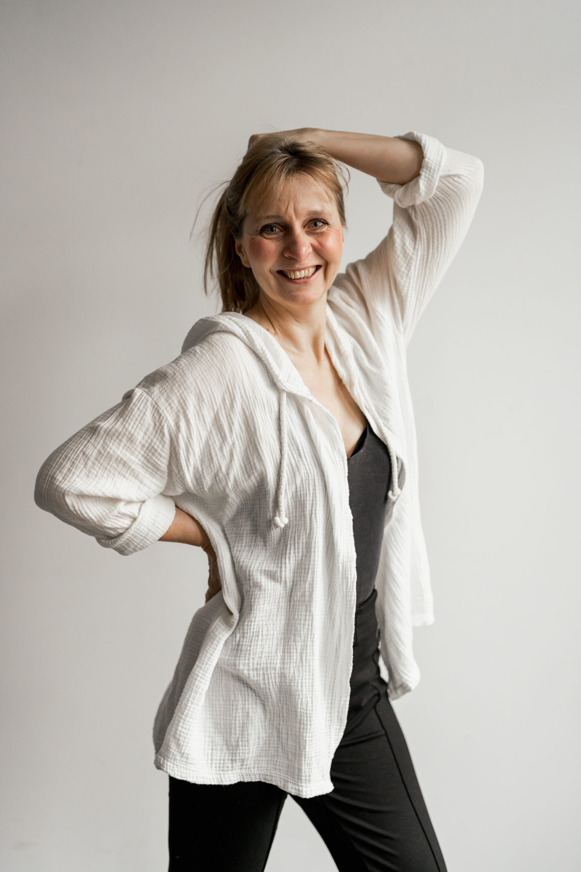 _74R5689-anwel Sedcard-Shooting Frau lächelt in Kamera vor weißer Wand