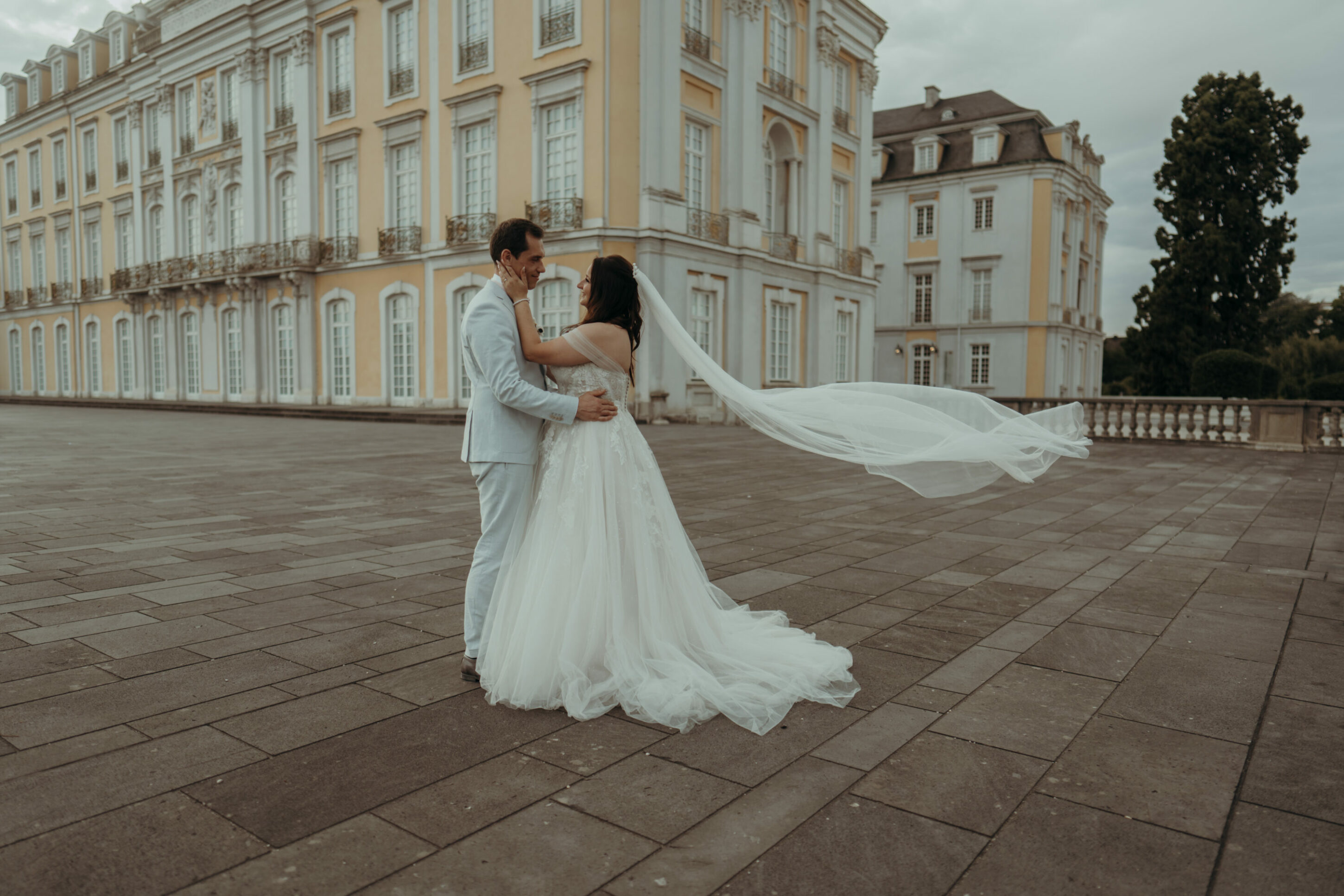 chrissandraafterwedding-6315-2 Kopie Hochzeitspaar vor Schloss, seitlich, Schleier fliegt im Wind