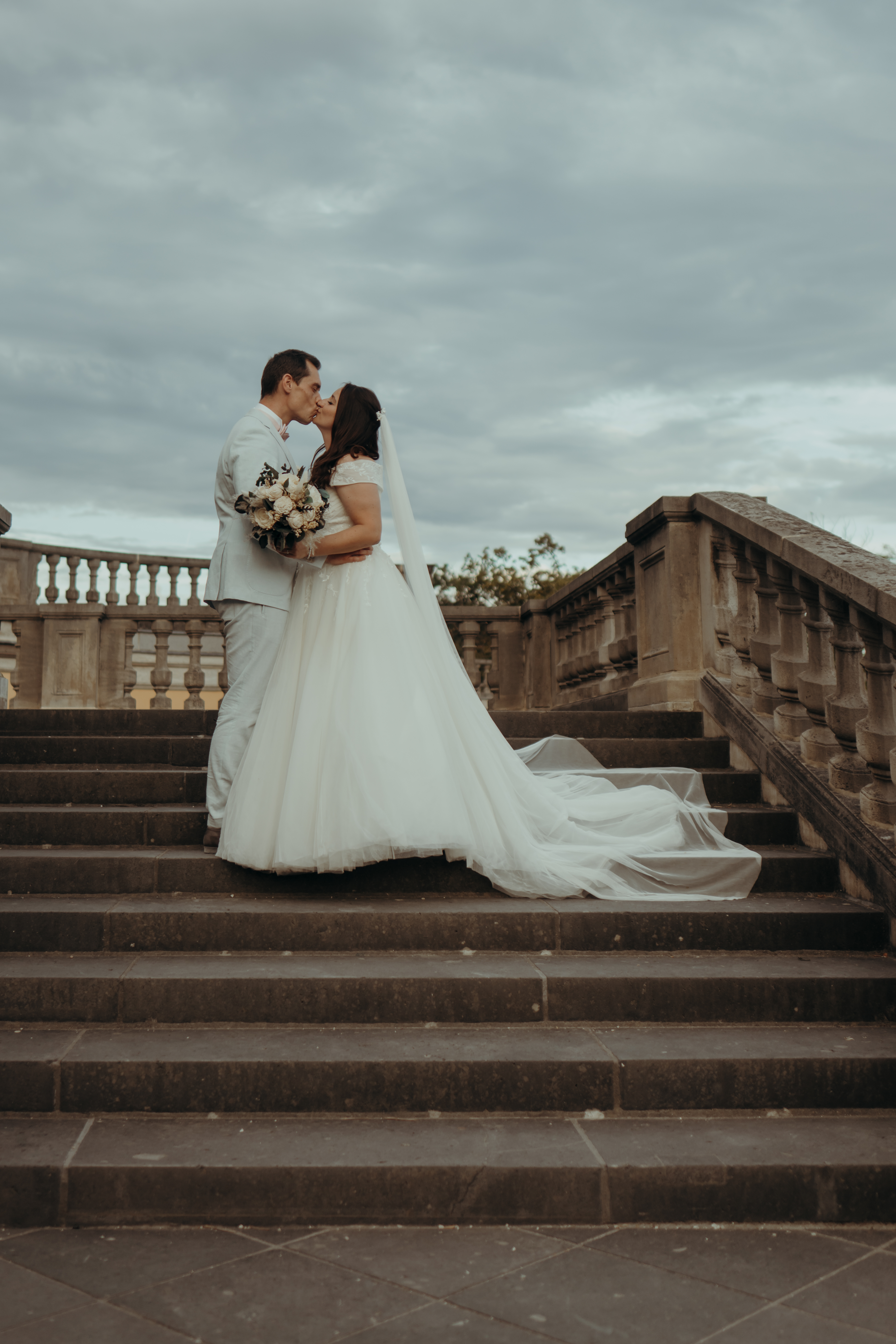 chrissandraafterwedding-6566-2 Kopie Brautpaar sich küssend auf Schlosstreppe, seitlich