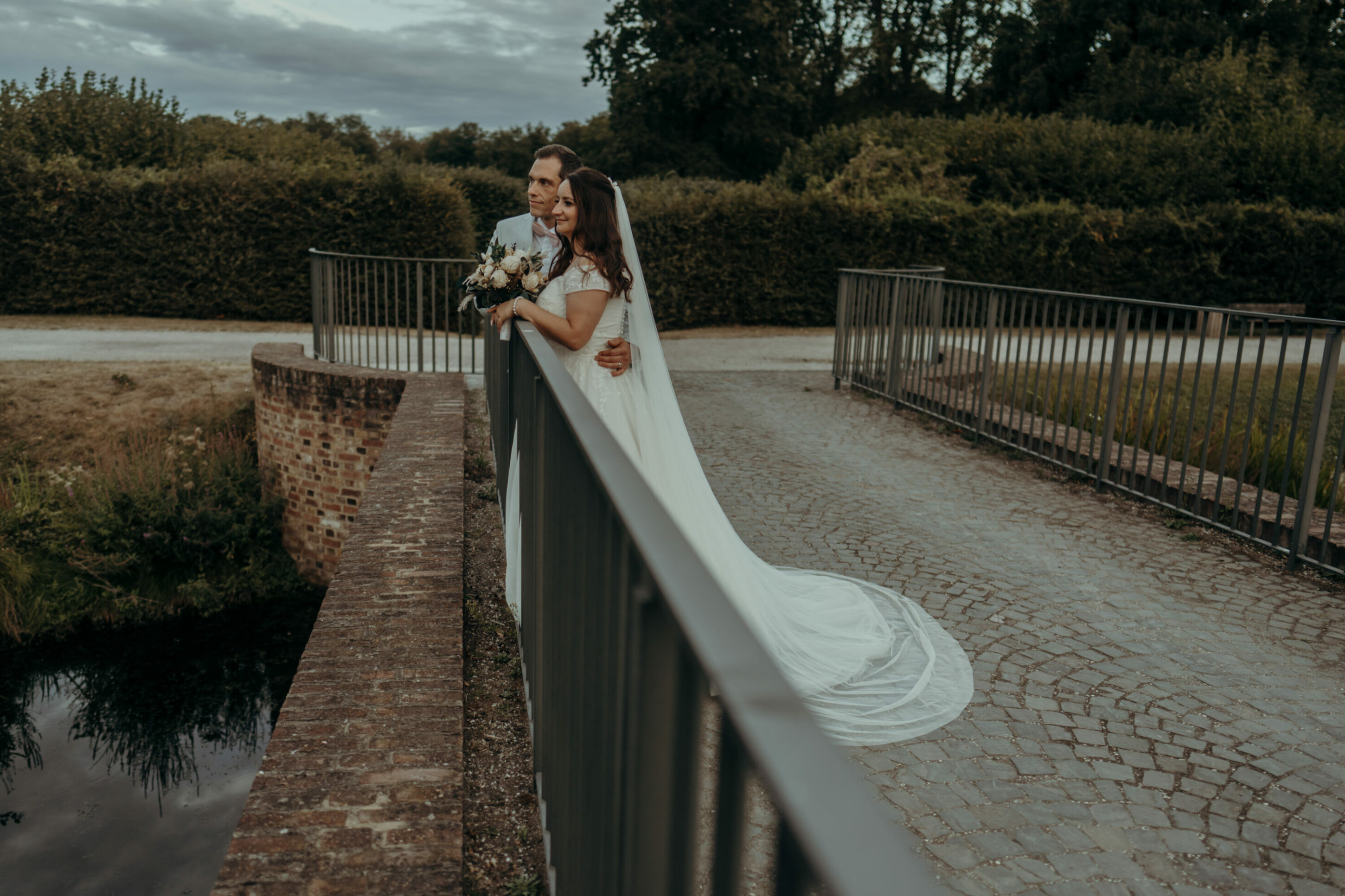 chrissandraafterwedding-7261-2 Kopie Brautpaar auf kleiner Brücke, in die Ferne schauend an Geländer