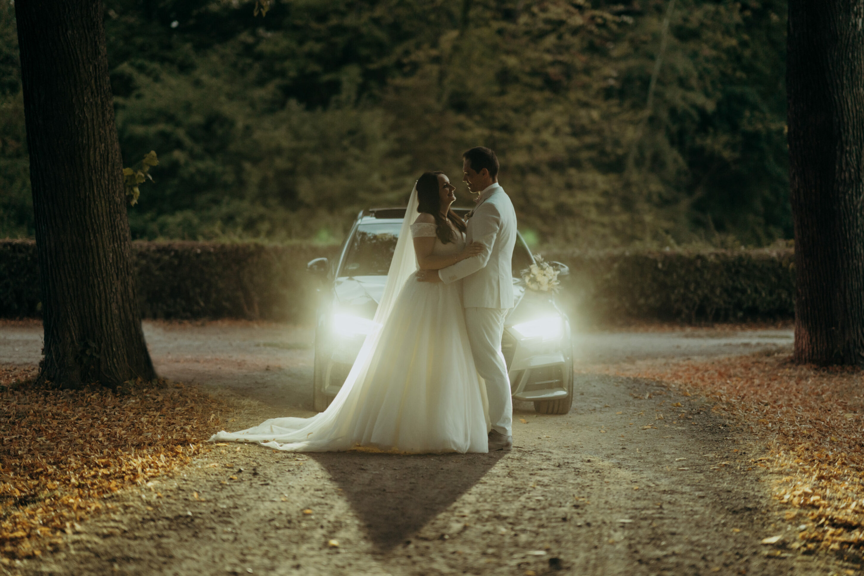 chrissandraafterwedding-7624-2 Kopie Brautpaar in Dämmerung vor Autoscheinwerfern sich in die Augen schauend